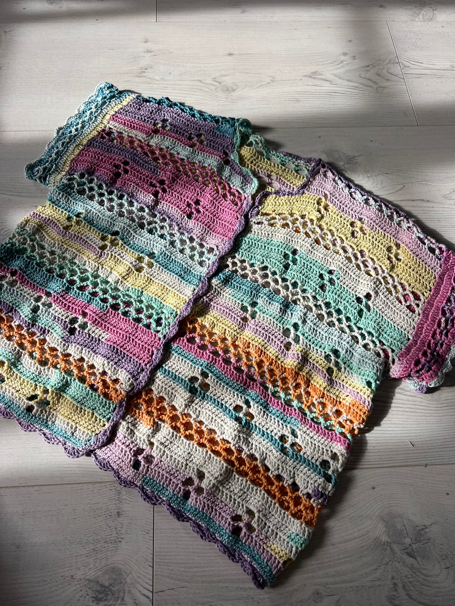Handmade crochet beach cover up featuring colorful granny stripe details and airy openwork stitches.