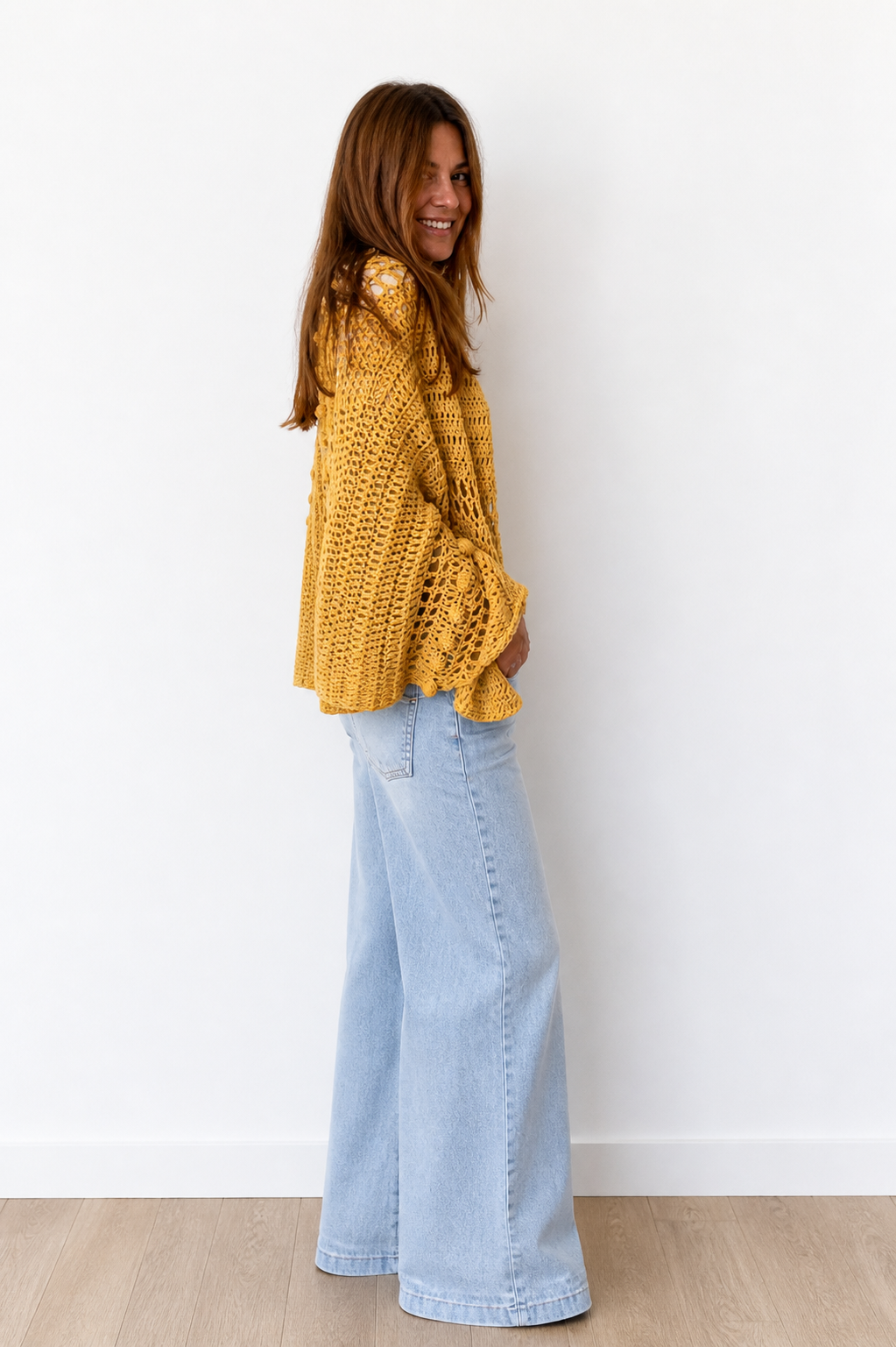 Woman wearing the Golden Hour Wrap crochet shawl, a soft and elegant layering piece for summer evenings.