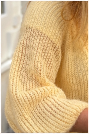 Front detail of a hand knitted top-down cardigan featuring a V-neck, button band and soft mohair texture.