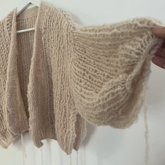 Soft oversized alpaca silk balloon cardigan hanging on a hanger, airy half fisherman rib stitch with light and cozy texture