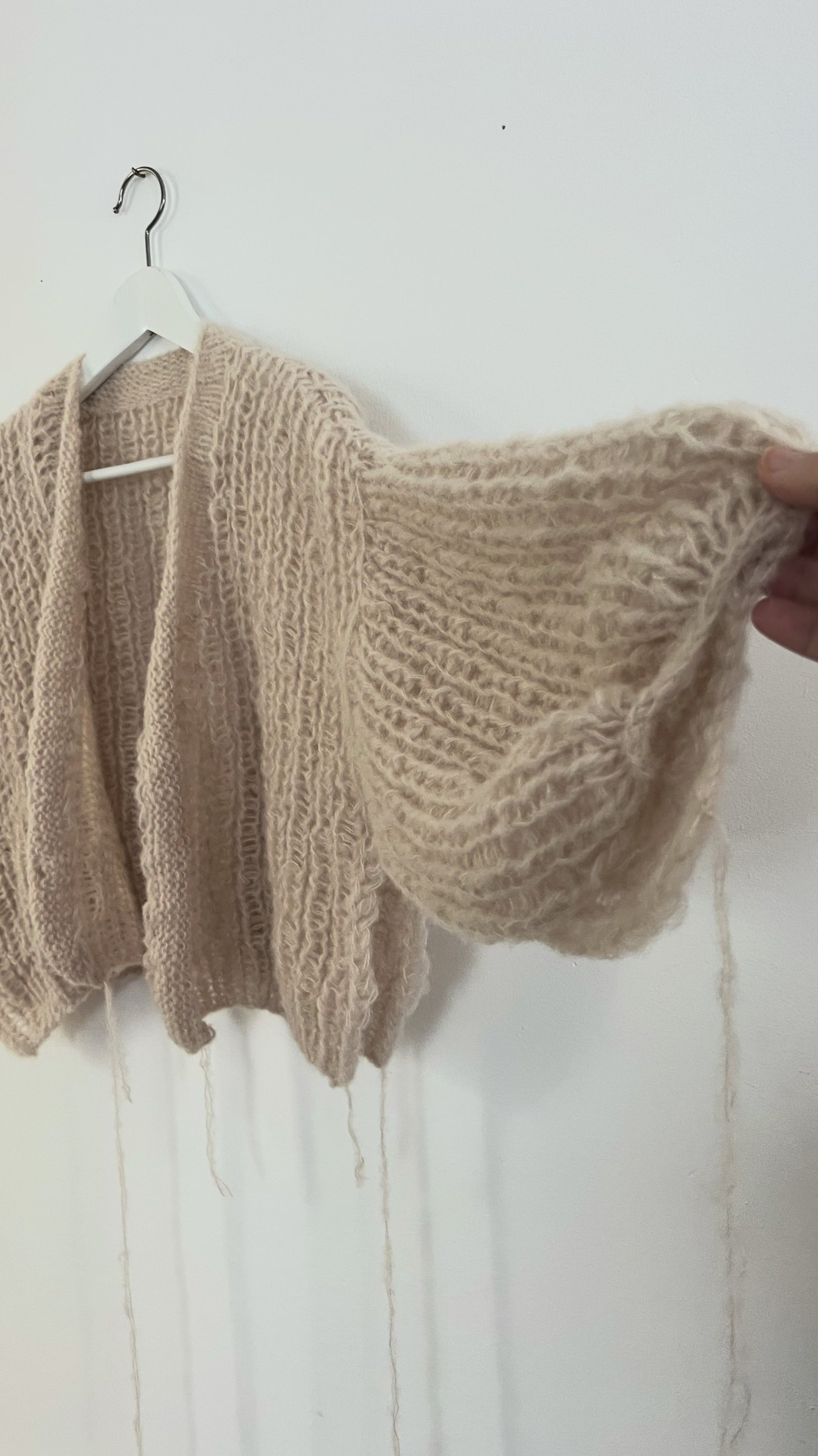 Soft oversized alpaca silk balloon cardigan hanging on a hanger, airy half fisherman rib stitch with light and cozy texture