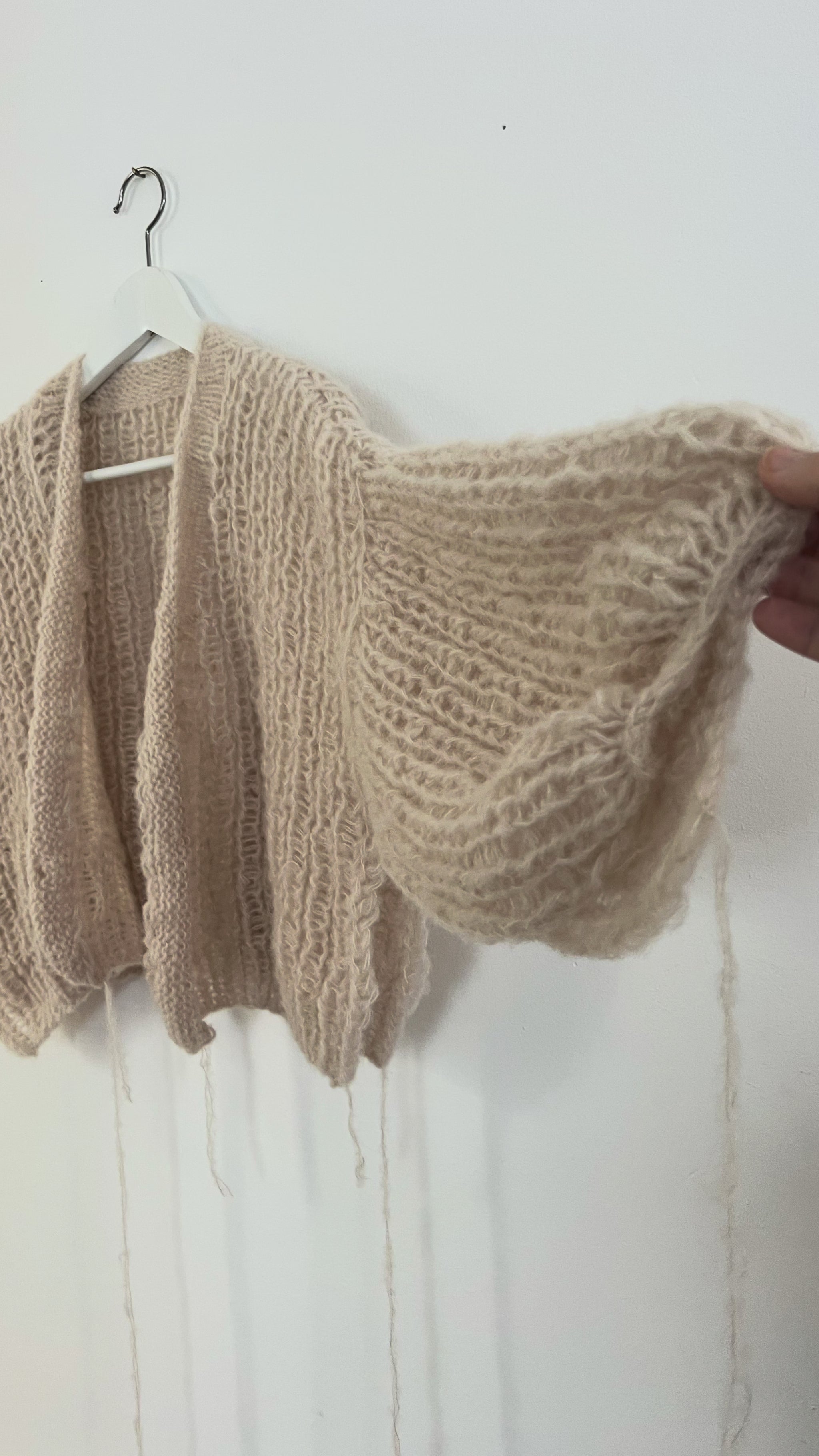 Soft oversized alpaca silk balloon cardigan hanging on a hanger, airy half fisherman rib stitch with light and cozy texture